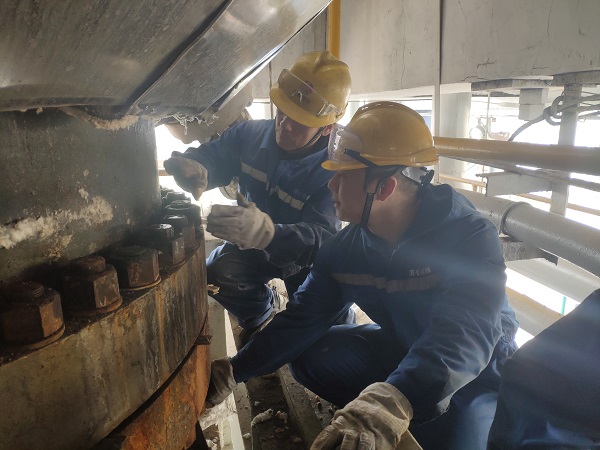 4月6日，機械修造部檢修二部張振華、盧超逸在檢修平臺處，進行4號氣化爐破渣機下降管短節(jié)法蘭螺栓的拆卸工作。.jpg